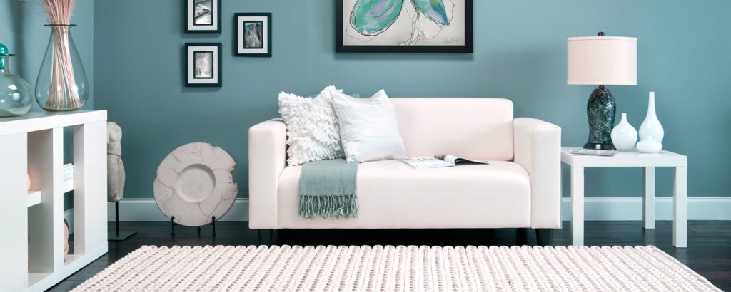 Белый диван на фоне голубой стены