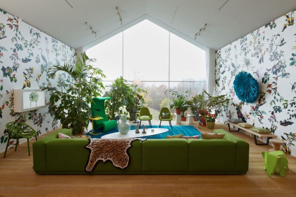 Фото комнаты с большим витражным окном и зелёным диваном