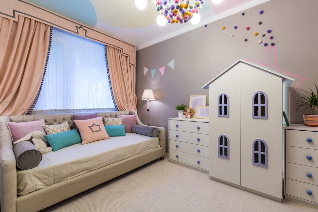 Интерьер детской комнаты с большим прямым диваном для сна у окна