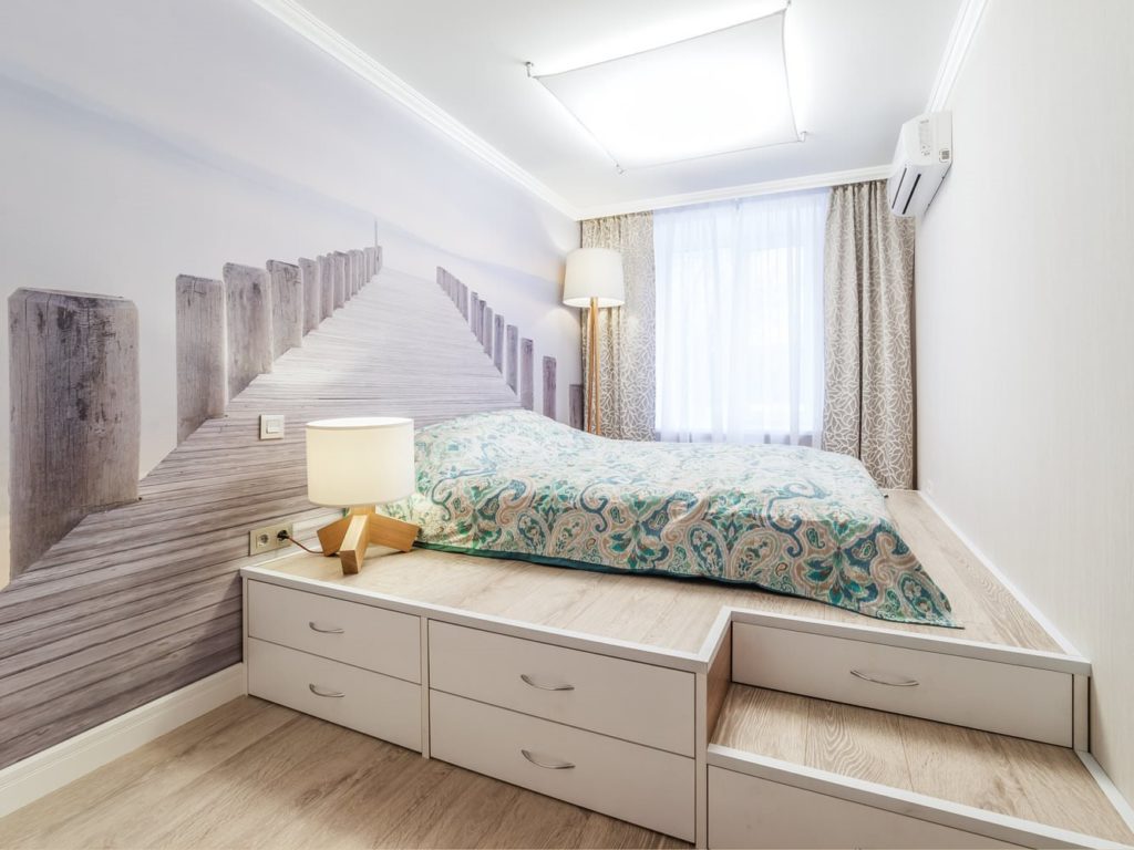 Кровать на подиуме с ящиками в интерьере комнаты