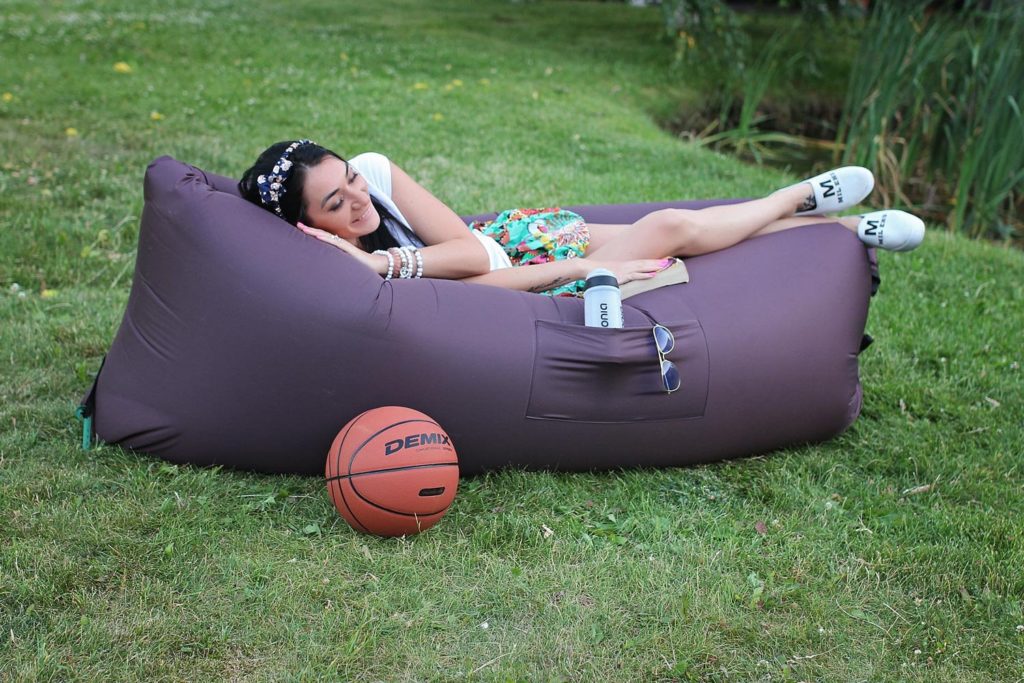Девушка отдыхает лежа на надувном дивана на природе