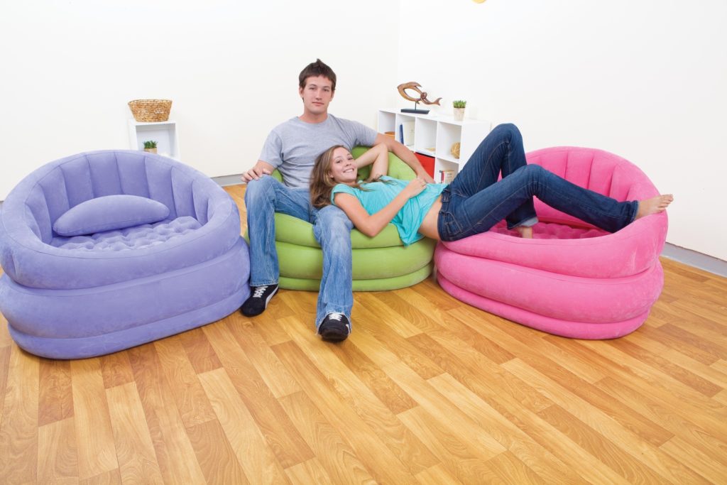 Пара молодых людей сидит на надувных диванах в комнате