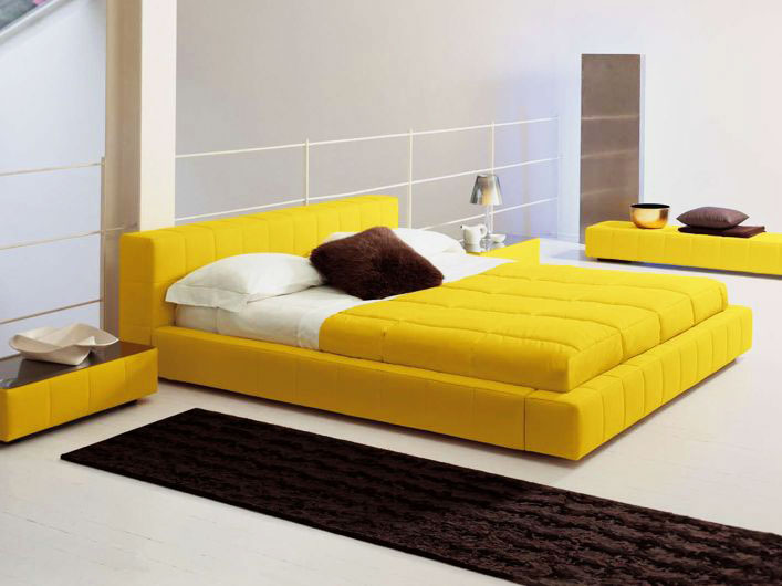 Современный интерьер просторной спальной комнаты с желтой кроватью