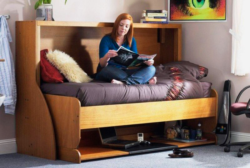 Девочка подросток читает журнал сидя на трансформируемой стол-кровати