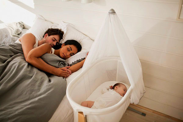 Младенец в колыбели рядом с кроватью родителей